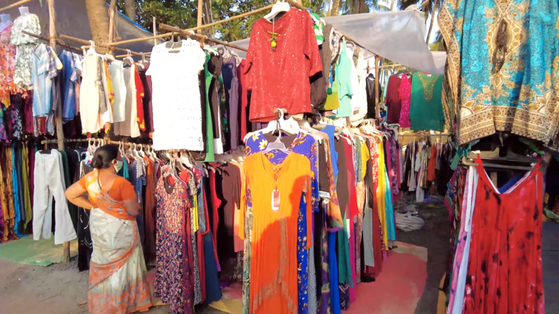 A Shopper Browsing Colorful Clothing Stalls at Anjuna Flea Market in Goa