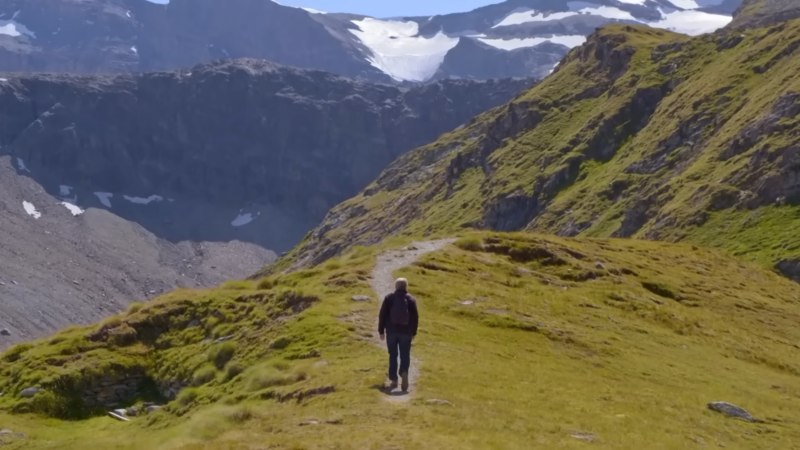 A Hiker Walks Along a Mountain Trail with A View of Zermatt and The Matterhorn in Switzerland