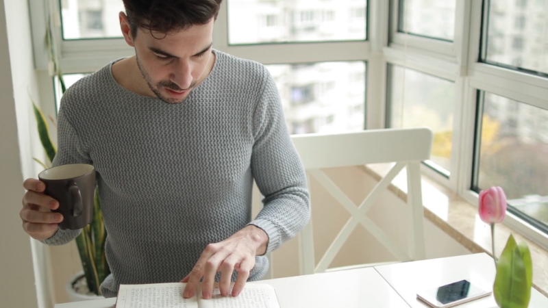 A man drinks coffee and reads a journal as part of his flexible morning routine