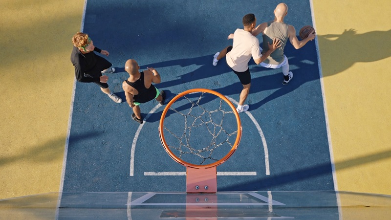 Top-down view of four men playing basketball on a colorful outdoor court, engaging in one of their active hobbies