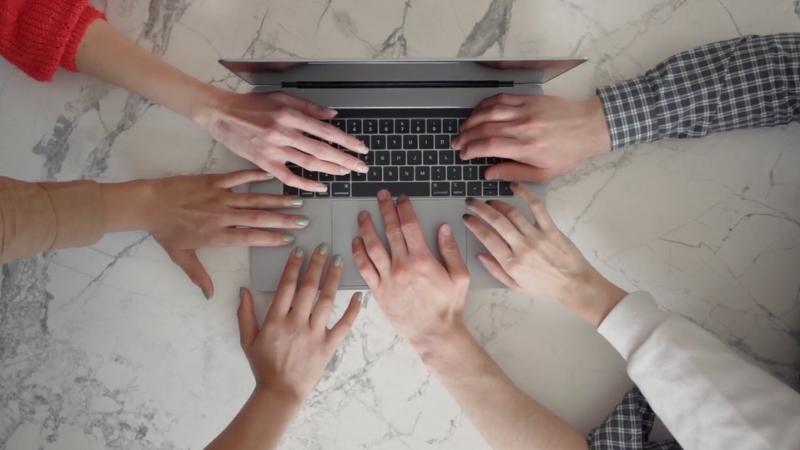 Several people working together on a laptop, collaborating to support a local brand initiative