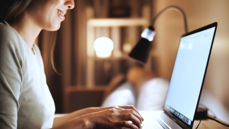Woman typing on a laptop at home, working on content to grow her brand visibility online