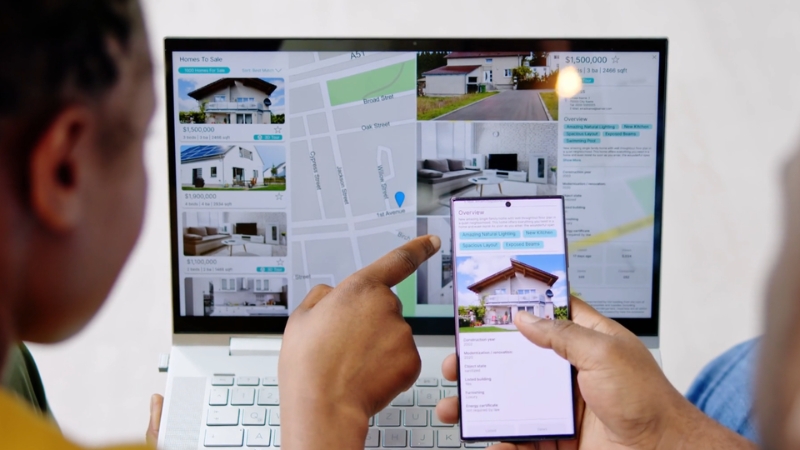 Two people check property listings online to find below-market price properties