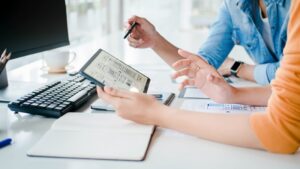 Two people review a tablet screen with wireframes, discussing intuitive UX improvements for better website performance and user retention