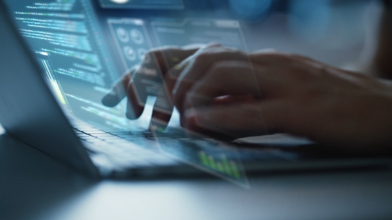Hands typing on a laptop with code on screen, illustrating regulation and trust in the AI-driven workplace