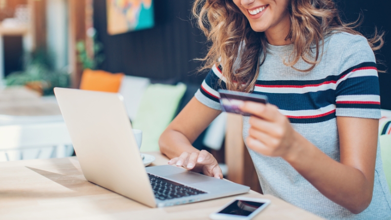 A woman using a laptop for online shopping while holding a credit card