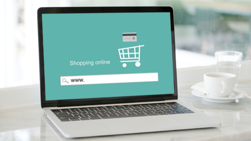 A laptop screen displaying a shopping cart graphic and search bar, representing e-commerce platforms