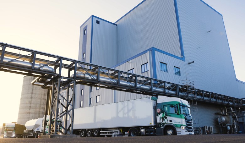 A large industrial building with several trucks parked in front