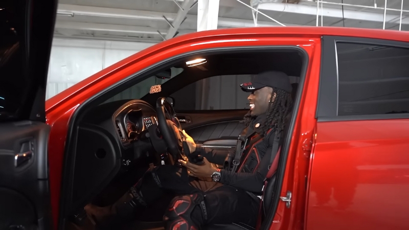 Kai Cenat sitting inside his red luxury car