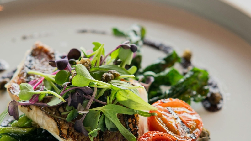 A gourmet dish topped with microgreens and roasted tomato highlights techniques that elevate restaurant presentation