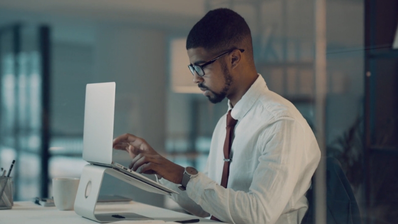 Man working on a laptop in an office, showing KYC compliance updates for businesses