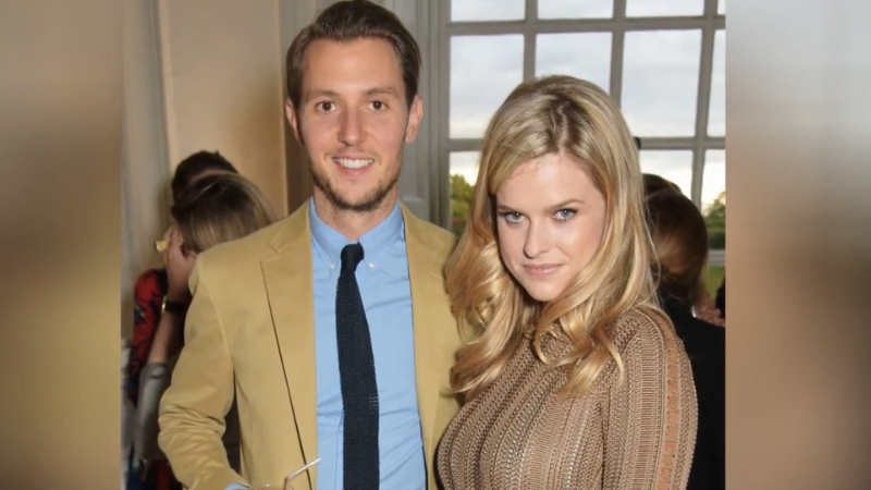 Alex Cowper-Smith and Alice Eve pose together at an indoor event near a large window