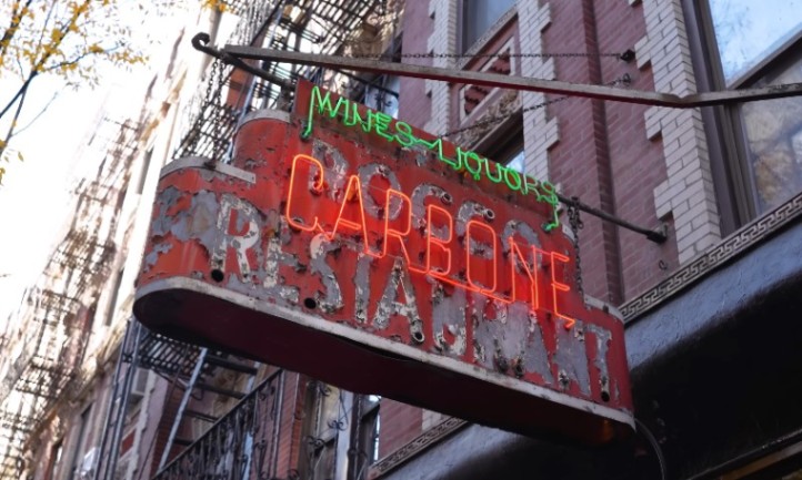 Neon sign for Carbone restaurant illuminated on the side of a building