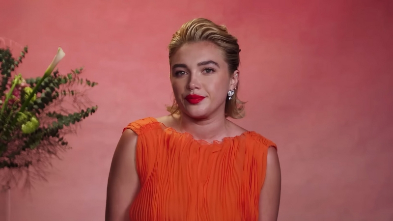 Florence Pugh poses in an orange dress with red lipstick during a interview shoot