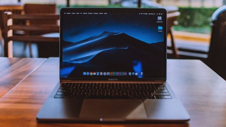 A MacBook Pro on a wooden table with the desktop screen visible used for recovering permanently deleted photos on Mac