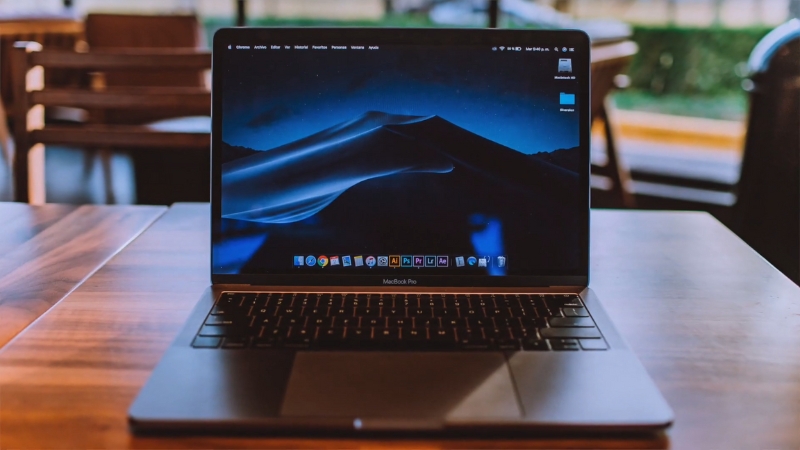 A MacBook Pro on a wooden table with the desktop screen visible used for recovering permanently deleted photos on Mac