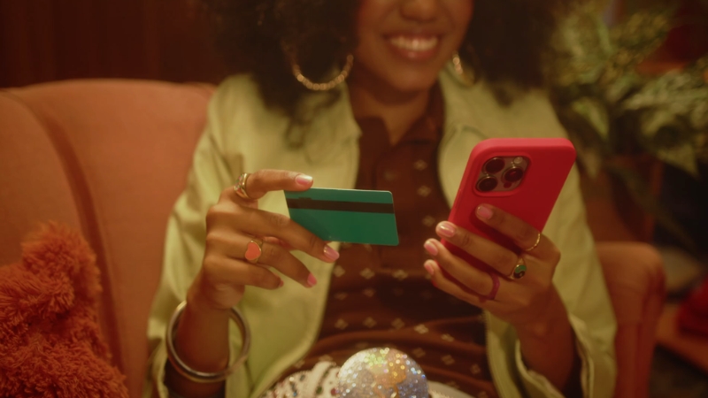 Woman holding a credit card and phone while making an online purchase