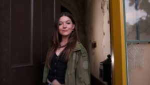 Katie Douglas stands in a doorway wearing a green jacket and black top
