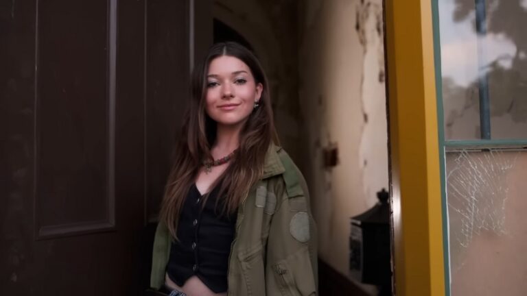 Katie Douglas stands in a doorway wearing a green jacket and black top