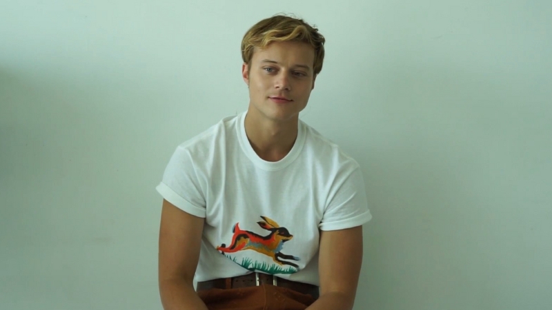 Rudy Pankow sits against a plain light background wearing a white T-shirt