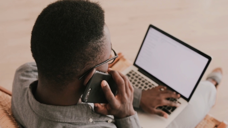 Man on a phone call while working on a laptop during a busy workday