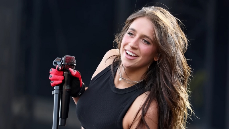 Tate McRae performs on stage with a black microphone