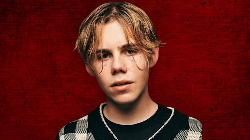 Kid Laroi poses against a red textured background