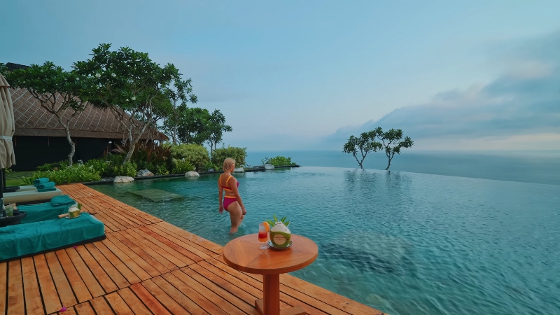 A woman stands by an infinity pool overlooking the ocean at one of the top luxury resorts in Southeast Asia