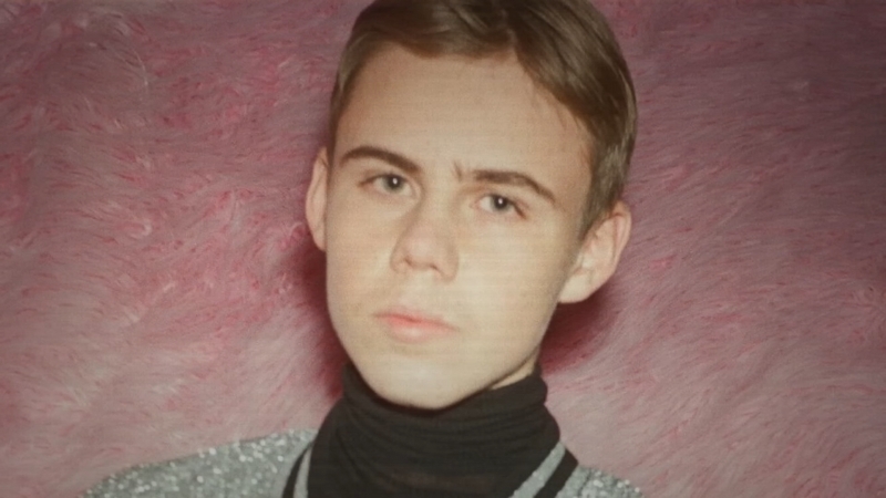 Kid Laroi looks directly at the camera in a soft pink background portrait