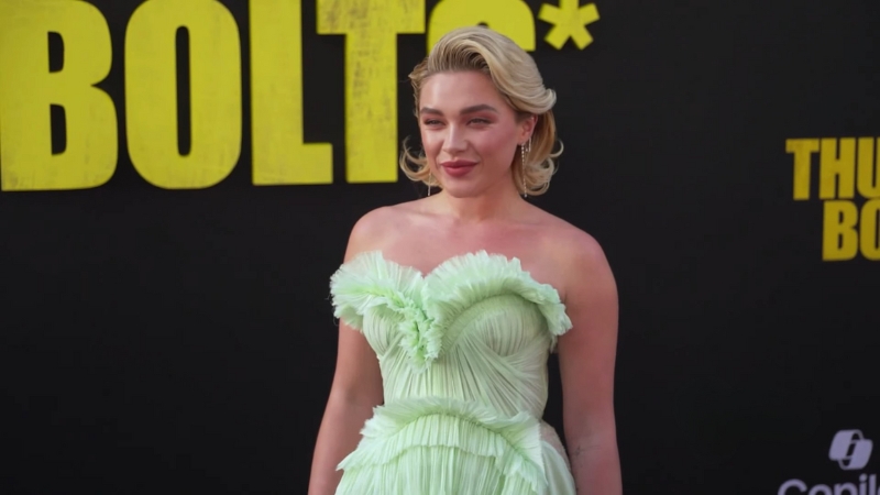 Florence Pugh poses on the red carpet in a light green ruffled gown at a film premiere event