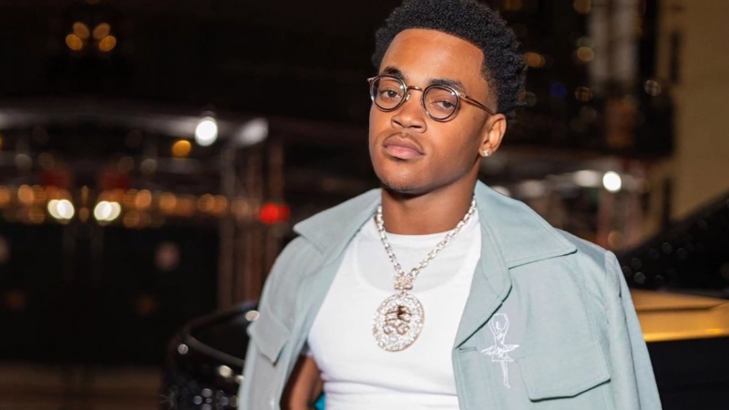 Michael Rainey Jr. standing confidently in stylish streetwear with glasses and a large chain during a night event