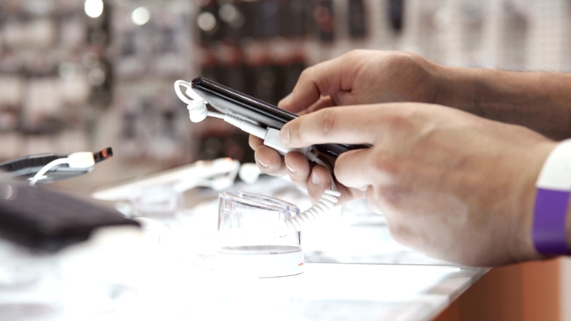 A person checks a smartphone display inside a mobile shop