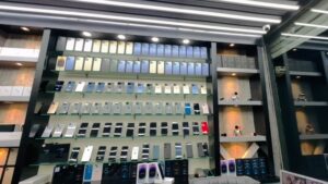 A small mobile shop displays rows of new and used smartphones on wall shelves