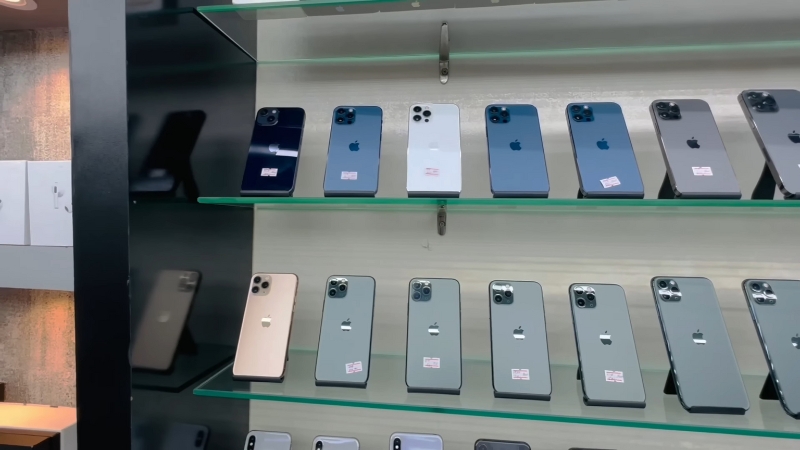 A shelf displays multiple iPhones inside a small mobile shop