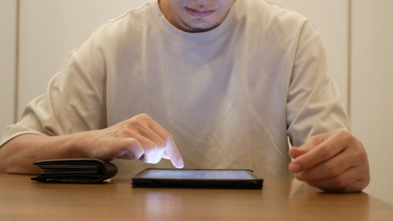 A person searches for suppliers on a tablet beside a wallet