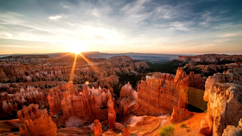 Sunrise light over Bryce Canyon hoodoos and layered red rock cliffs under a wide sky