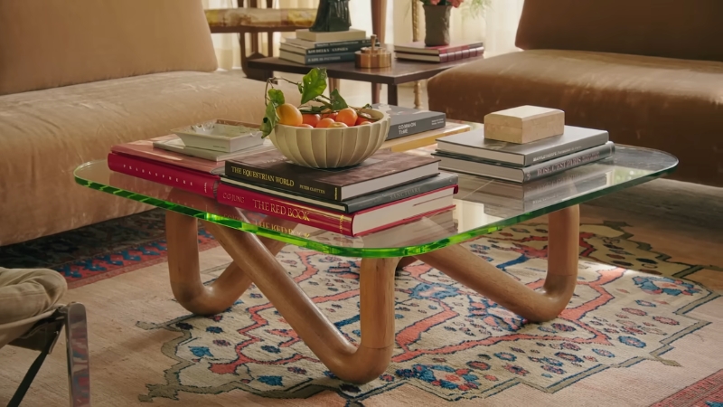 Glass coffee table with stacked books and a bowl of fruit in Dakota Johnsonโs vintage-inspired Hollywood living room
