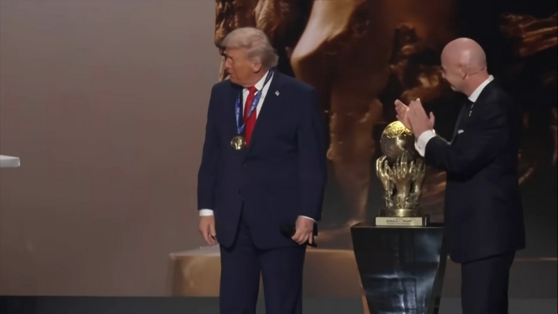 Donald Trump stands on stage beside the FIFA World Cup trophy during a ceremony presentation
