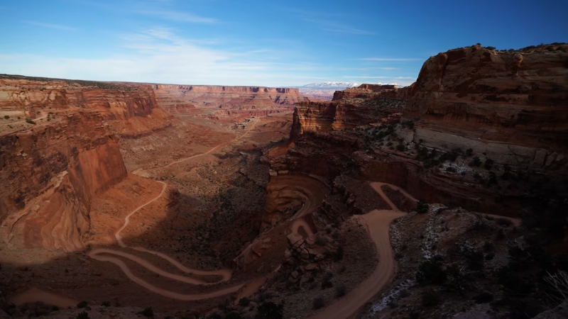 Wide canyon view with winding dirt road and layered red rock cliffs in Utah desert