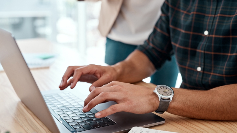 Person types on a laptop while working on brand content creation tasks