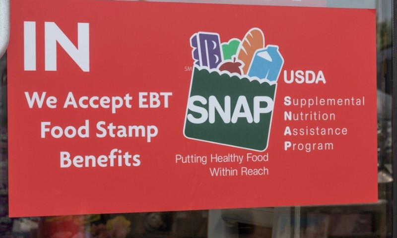 Red sign indicating acceptance of EBT food stamps, featuring the SNAP logo with groceries