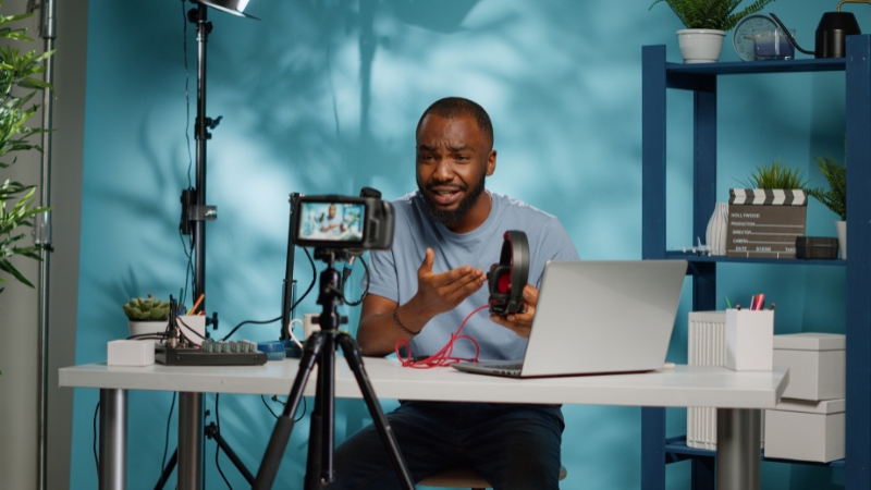 Person records video at a desk with camera, lights, and laptop setup