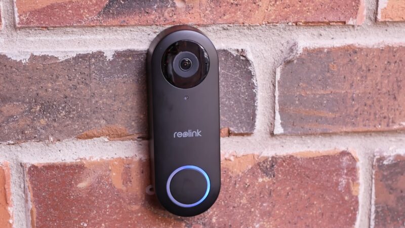 Reolink video doorbell mounted on a brick wall with a visible camera and lit button