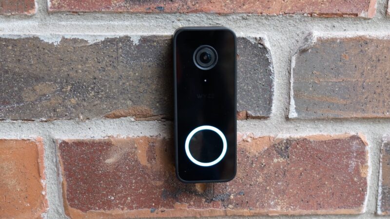 Wyze video doorbell mounted on a brick wall with a lit circular button and front camera visible