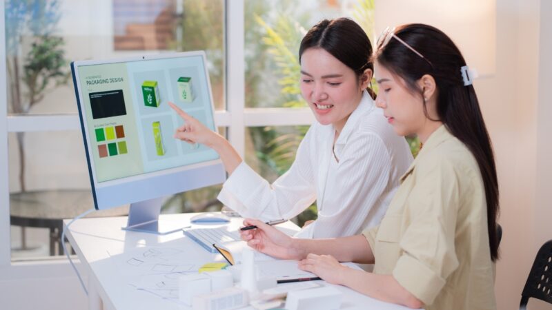 Two team members review an AI product concept on a large office screen