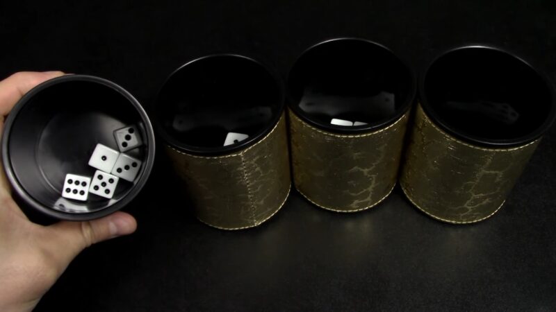 A player checks dice inside a cup during a Mia bluffing game