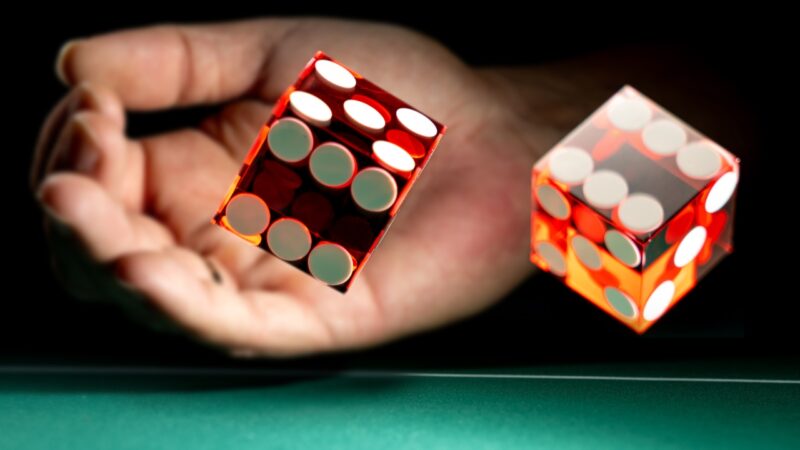 A player rolls red dice across a green table during a tense dice game