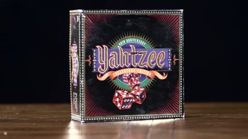 A Yahtzee game box sits on a wooden table with dice artwork on the front
