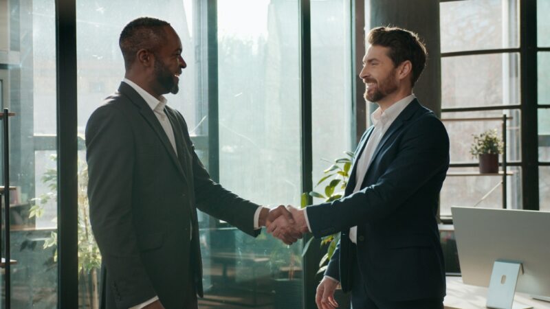 Two entrepreneurs shake hands in a bright modern office after a business talk