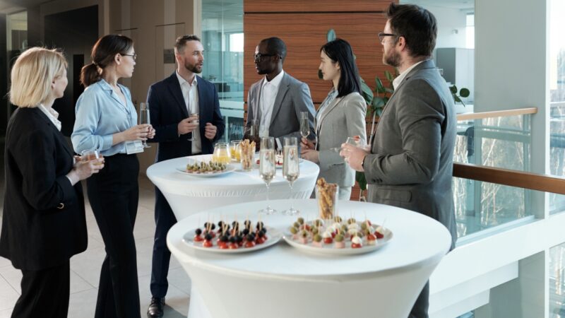 Business professionals talk at a corporate reception with drinks and light snacks